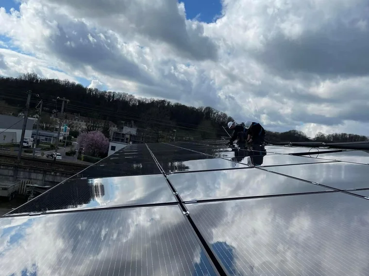Deux techniciens des Chantiers du Barrois intervenant sur une rangée de panneaux photovoltaïques en toiture