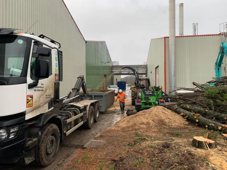 Chantier de terrassement avec camion polybenne devant un bâtiment industriel